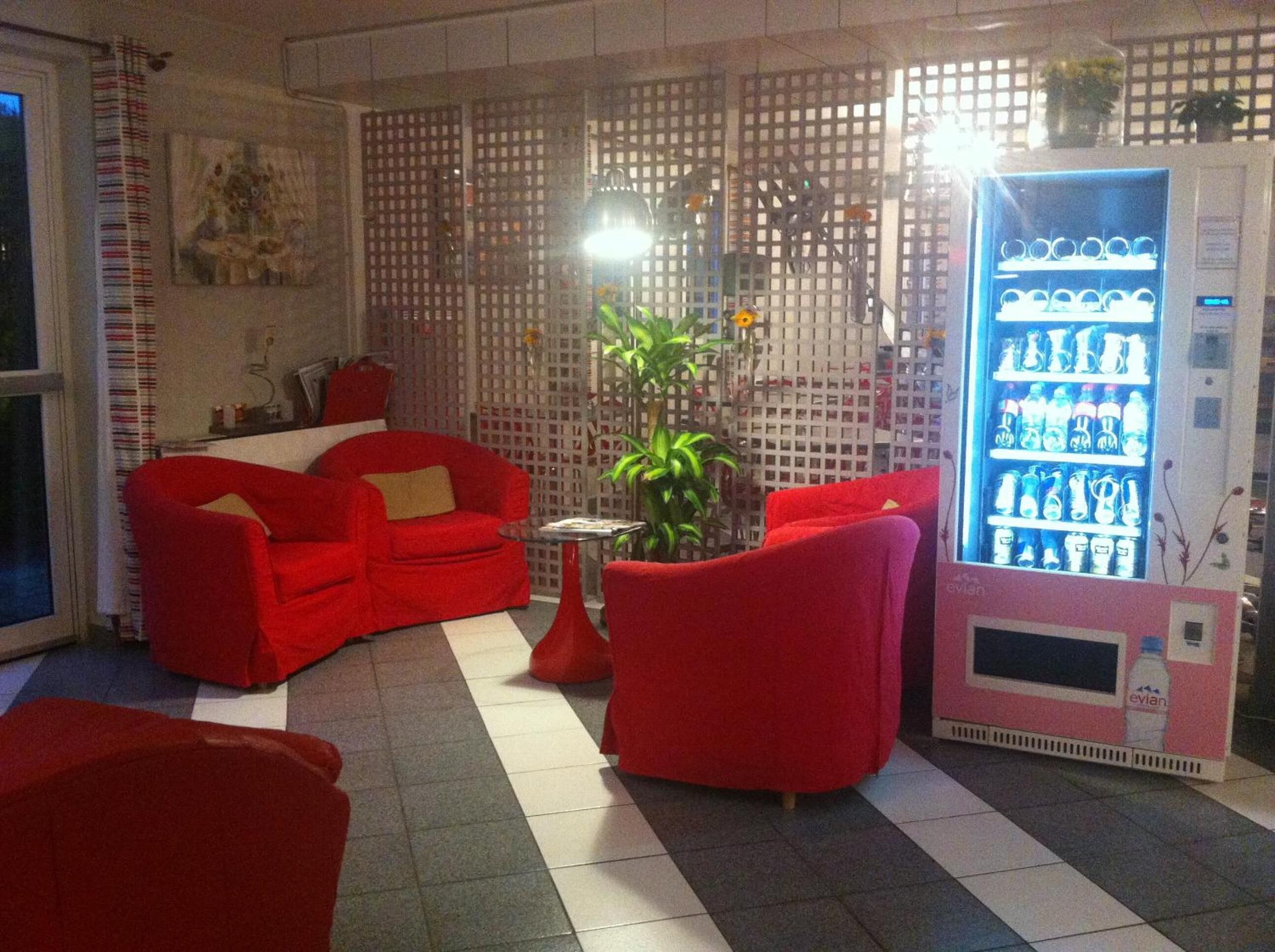 Een kamer met rode meubels, een plant en een automaat voor drankjes.