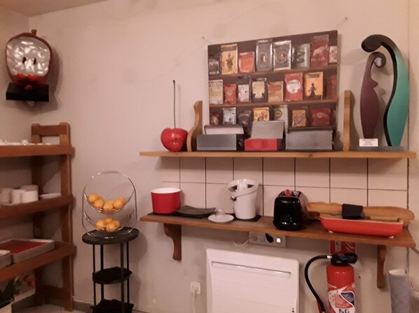 Una cocina con estantes de madera, un frutero, un hervidor, un tostador y un extintor.