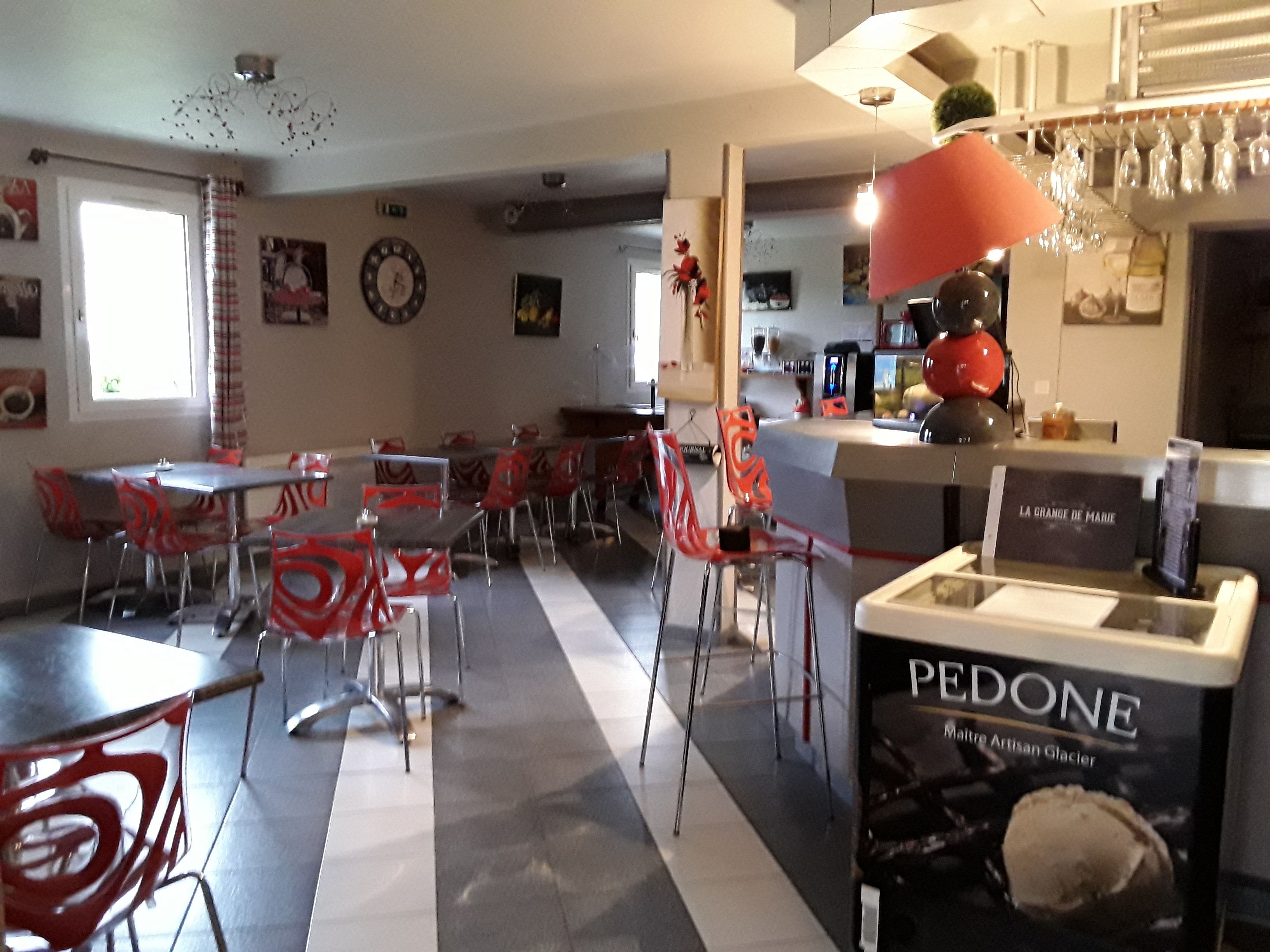 Een eetgedeelte met rode stoelen en tafels, een bar met een bord waarop 'LA GRANDE DE MARIE' staat, en een presentatie van 