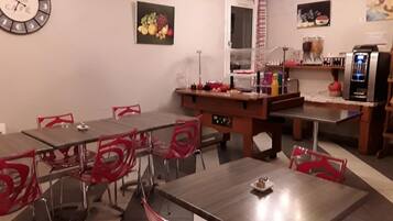 Un restaurante con varias mesas y sillas, un reloj y diferentes electrodomésticos de cocina.