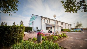 A hotel with a large sign reading "HOTEL" and a parking area with a van. - La Grange de Marie (Nitry)