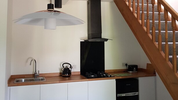 A compact kitchen with a built-in stove, a sink, and a kettle. - Church View (Huddersfield)