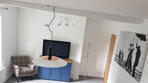 A modern living room with a round table, a sofa, a television, and a painting on the wall. - Church View (Huddersfield)