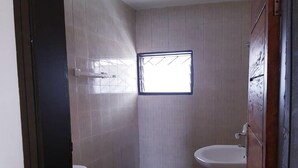 A small, compact bathroom with a toilet, sink, and a small window.