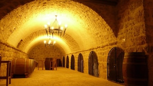 Uma adega de pedra com barris de madeira e um candelabro.