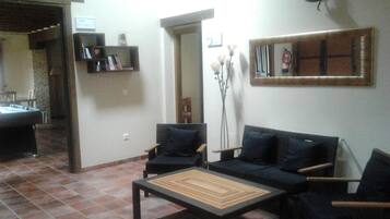 Una sala de estar con mesa de billar, dos sofás negros, una mesa de centro y una estantería.