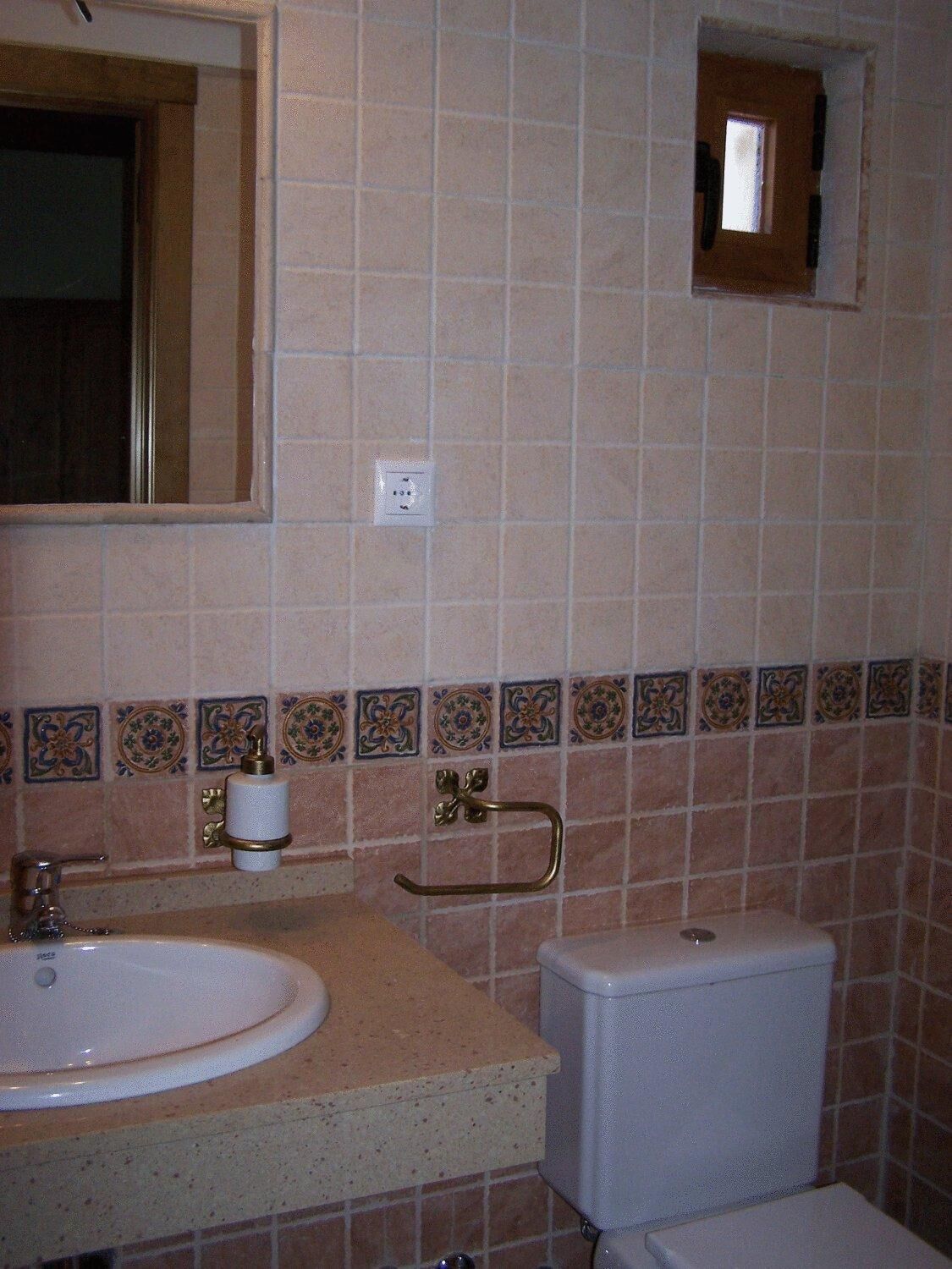 Un baño con lavamanos, inodoro y espejo.