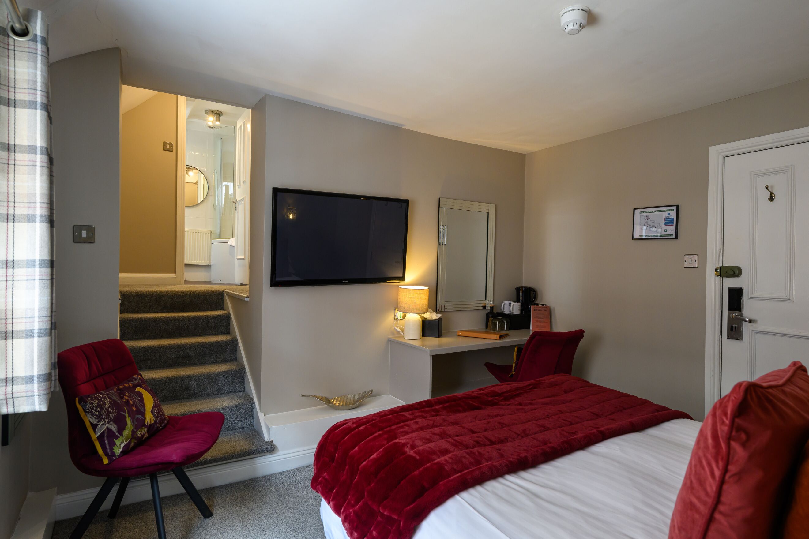 Habitación de hotel con cama, escritorio, silla, televisor y una escalera que lleva a un baño.