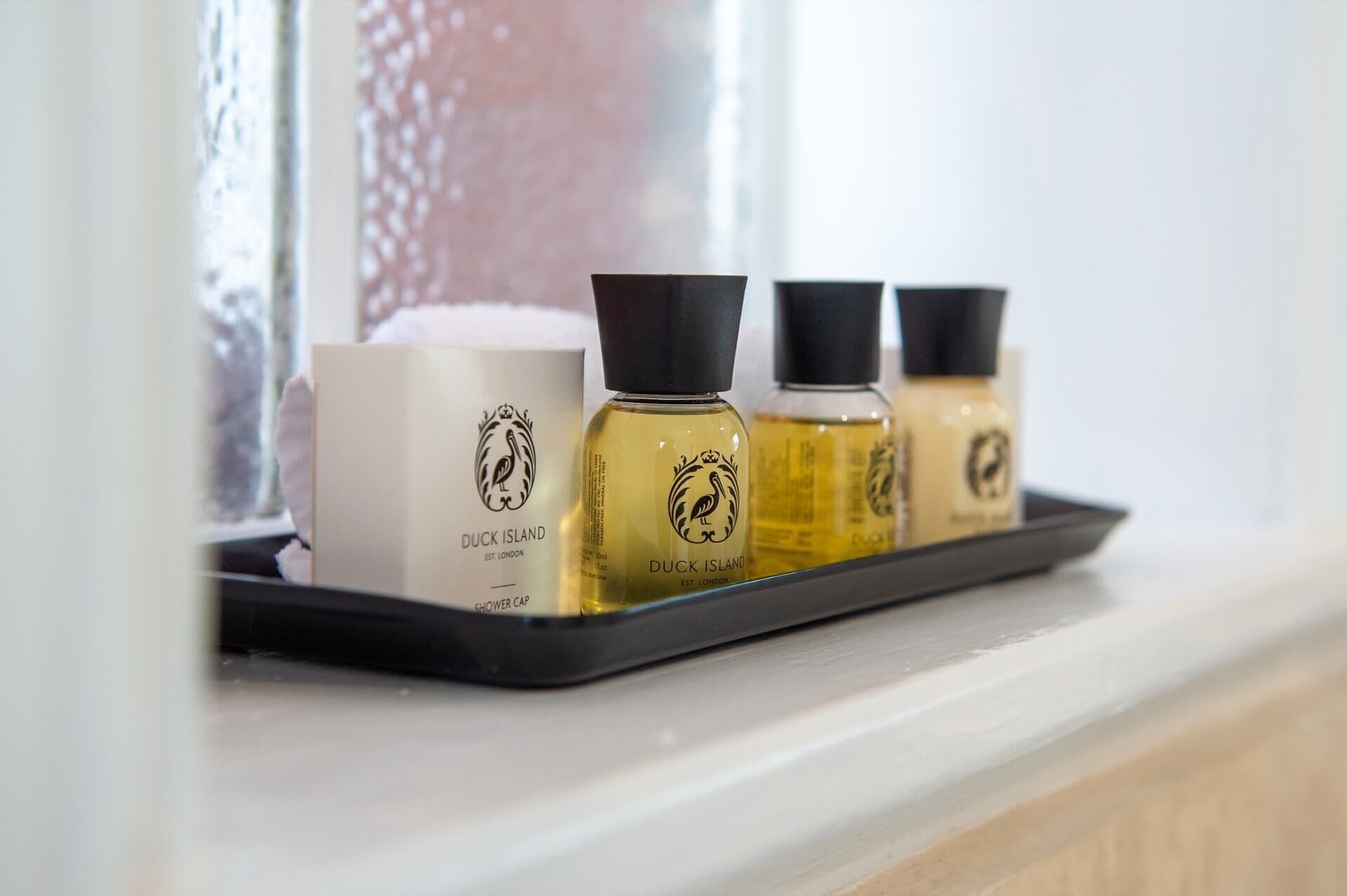 A tray with three Duck Island shower caps and a box on a window sill.