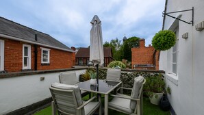 Une terrasse avec une table et des chaises, un parasol et des plantes en pot.