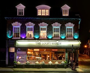 Un edificio con ventanas iluminadas y un cartel que dice 'The Loopy Shrew'.