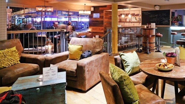 Un espace salon confortable avec des canapés en cuir, une table basse et un bar en arrière-plan.