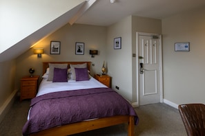 A bedroom with a bed, nightstands, a door, and wall-mounted lamps. - The Loopy Shrew (Shrewsbury)