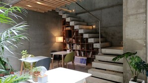 Ein modernes Interieur mit Treppe, Bücherregalen und einer Essecke mit Stühlen und Tisch.