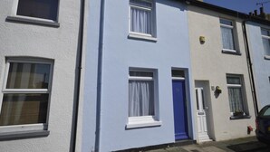A row of terraced houses with white and light blue exteriors, white-framed windows, and a blue door. - Victorian Rose Cottage (Deal)