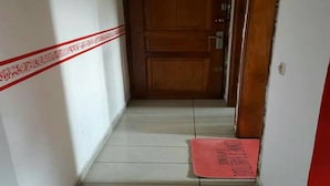 A narrow hallway with a wooden door at the end, a red mat on the floor, and a white wall with a red decorative border. - Les Residences Rima 9 (Abidjan)