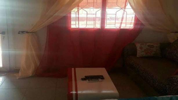 A room with a bed, a small table, a sofa, and a window with curtains. - Les Residences Rima 9 (Abidjan)