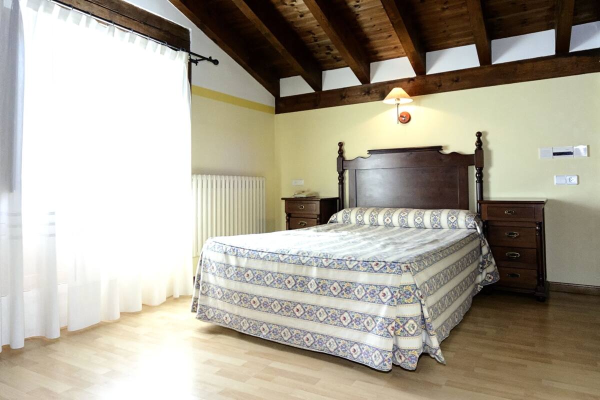 Un dormitorio con estructura de cama de madera, una mesita de noche, una lámpara y un radiador.