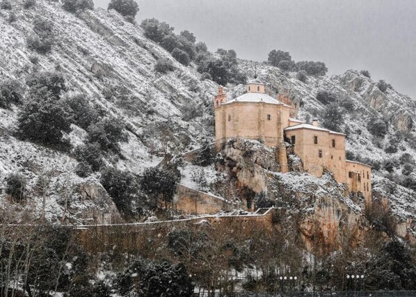Un edificio histórico con una torre redonda, ubicado en una colina cubierta de nieve.