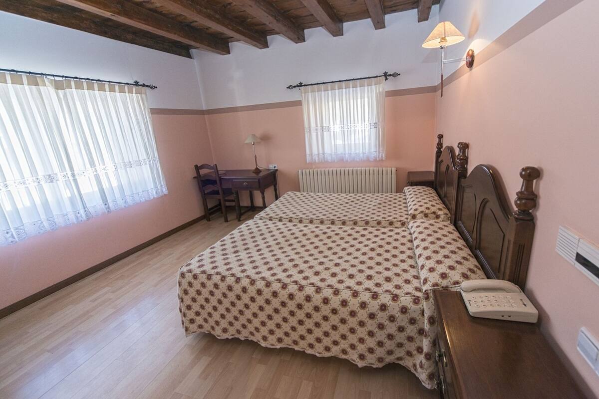 Un dormitorio con una cama de madera, un escritorio y una silla.