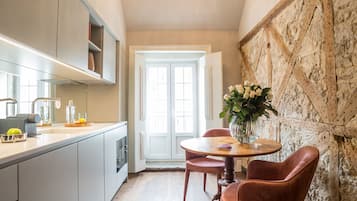 A kitchen with wooden flooring, a chandelier, and a dining area with a table and chairs.