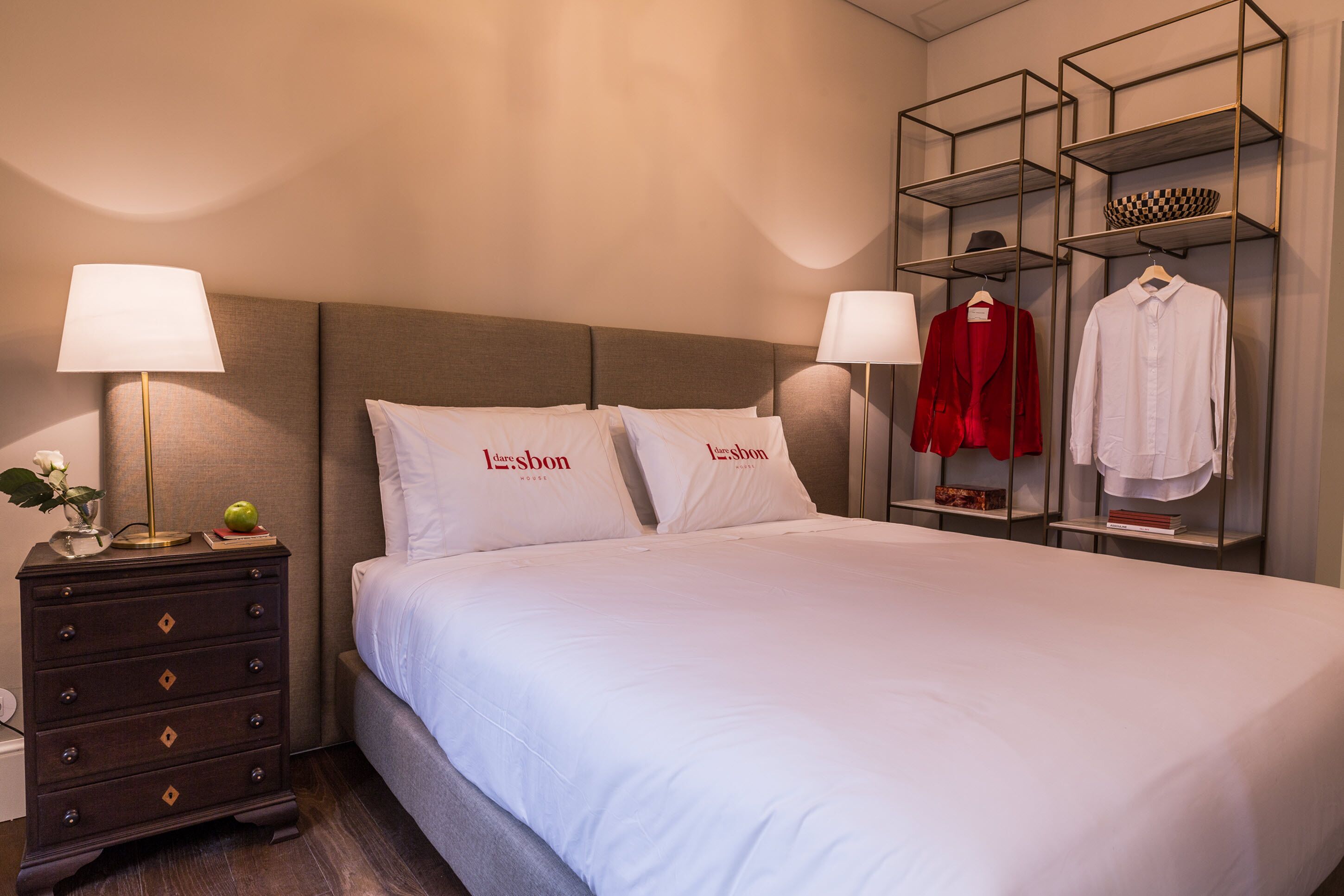 Een hotelkamer met een bed, twee nachtkastjes, een kaptafel en een kledingrek.