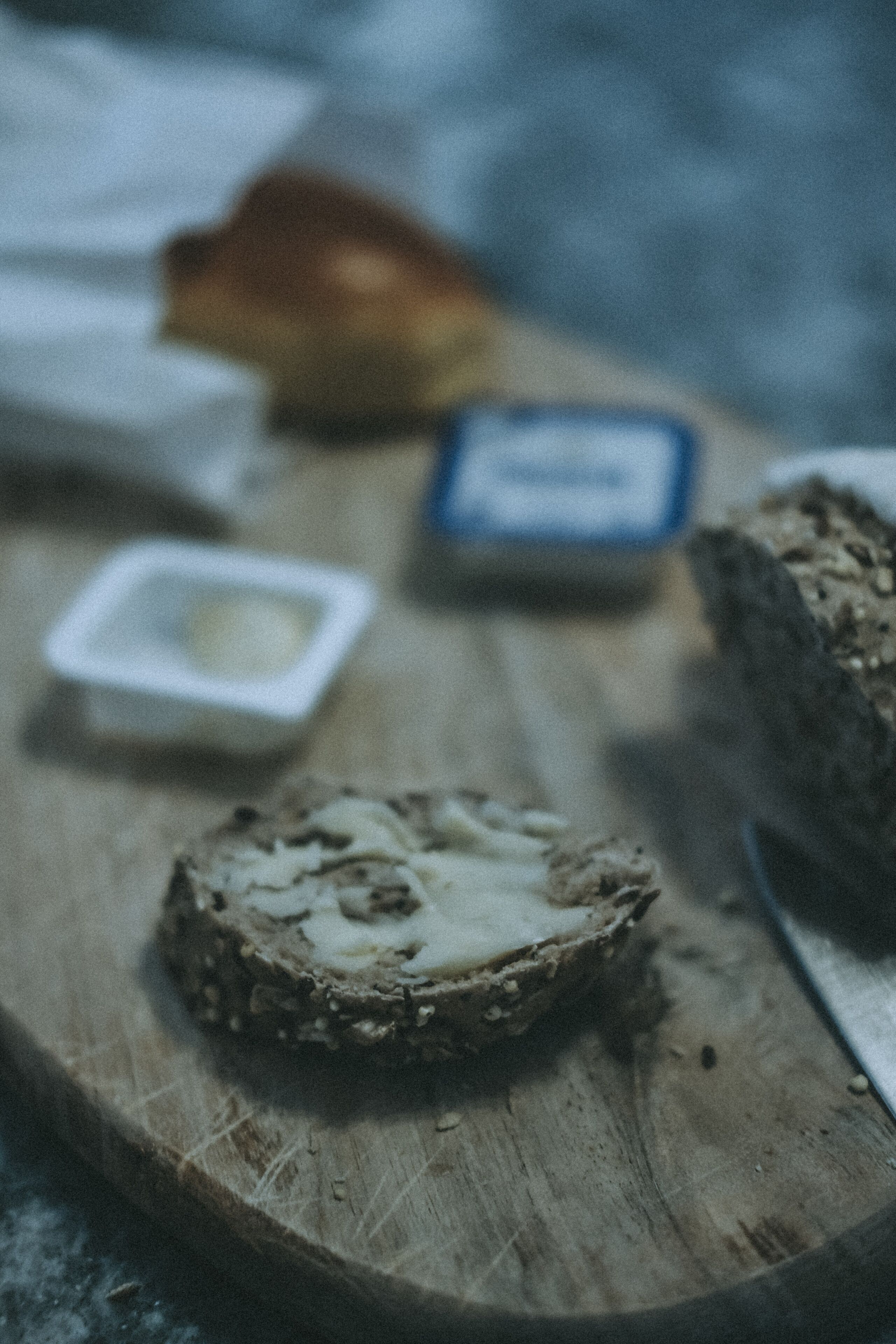 Una tabla de madera con una porción de queso y un tazón pequeño de mantequilla.