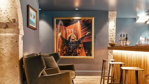 Un espace salon confortable avec un bar, des meubles en bois et une grande œuvre d’art encadrée au mur.