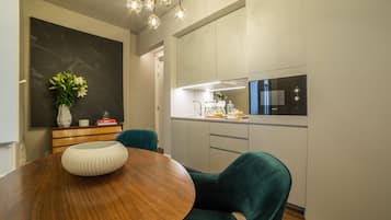 A modern dining area with a wooden table, teal chairs, and a black vase with flowers.