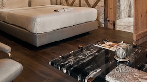 Ein Schlafzimmer mit einem Bett, Nachttischlampen, einem Holzschrank und einem Couchtisch mit Marmoroptik.