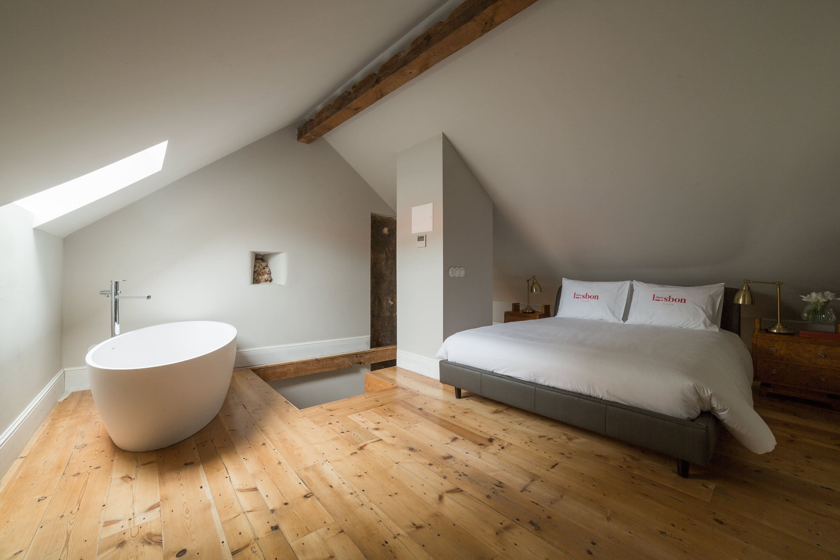 A bedroom with a large bed, a built-in bathtub, and a sloped ceiling.