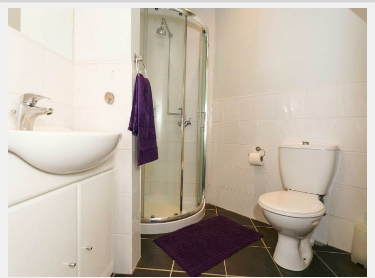 Ein Badezimmer mit einem weißen Waschbecken, einer Toilette und einer Duschkabine.