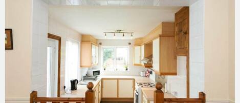 A kitchen with wooden cabinets, a central island, and a view to the outside.