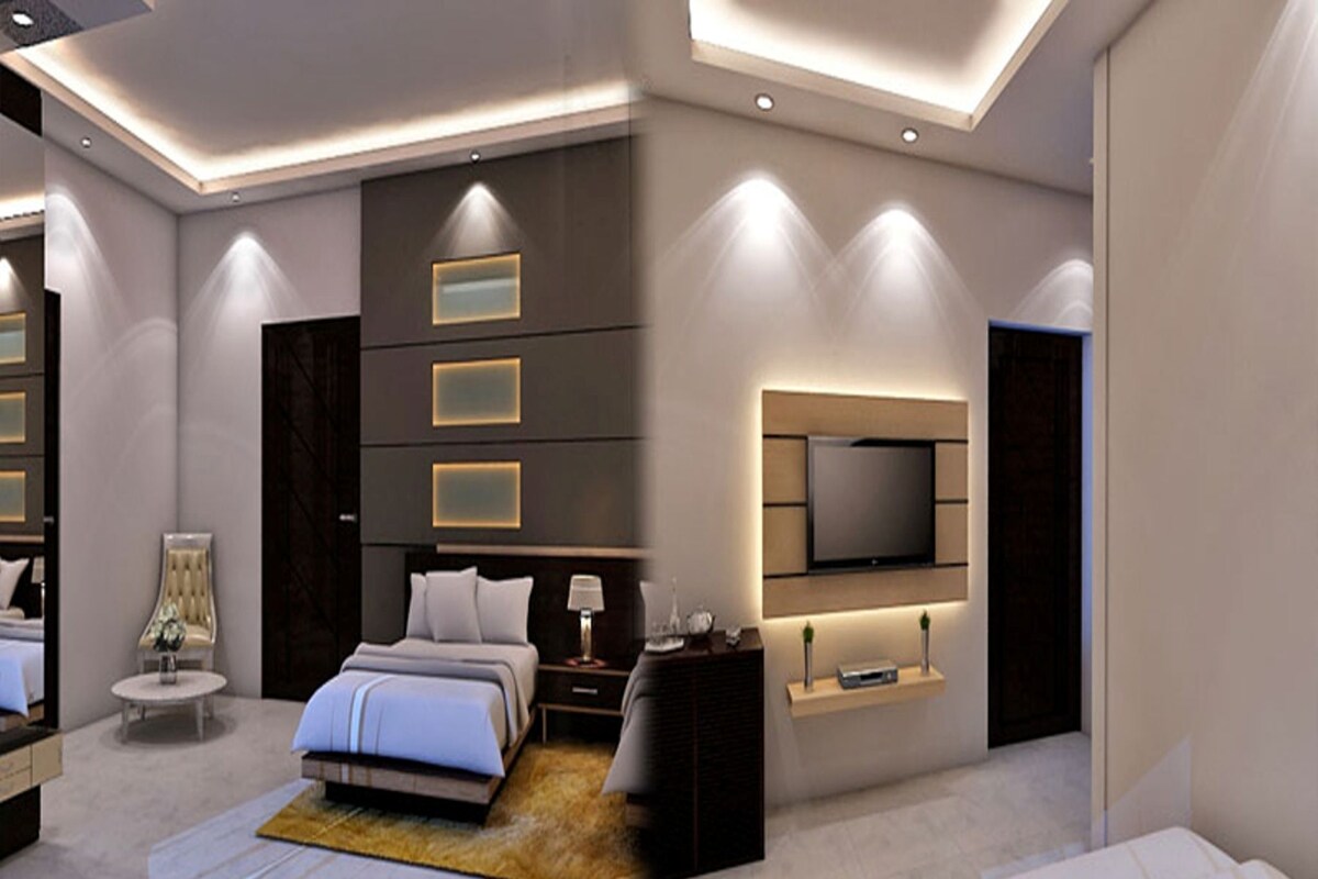 A modern bedroom with a bed, bedside tables, a TV mounted on the wall, and a large mirror.
