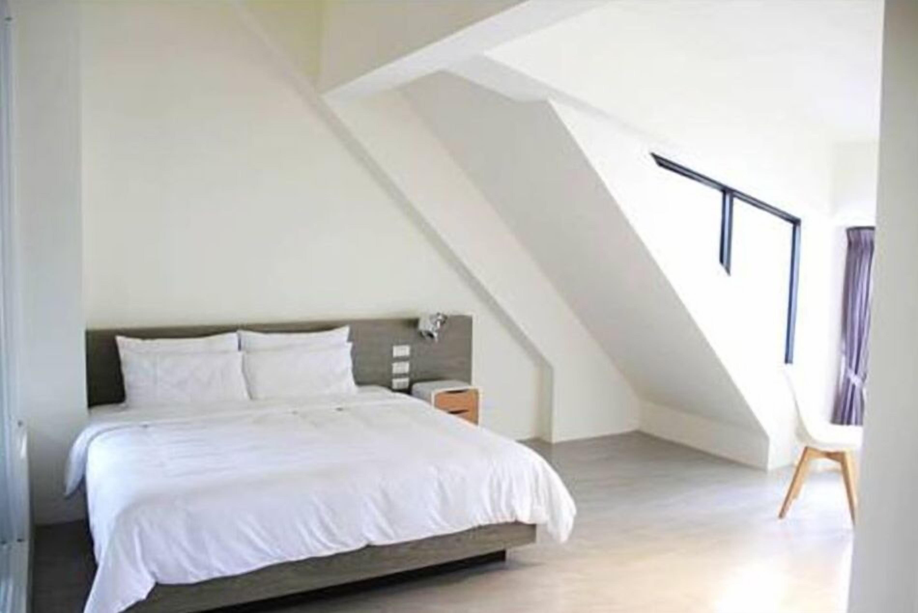 A bedroom with a bed, a nightstand, and a chair.