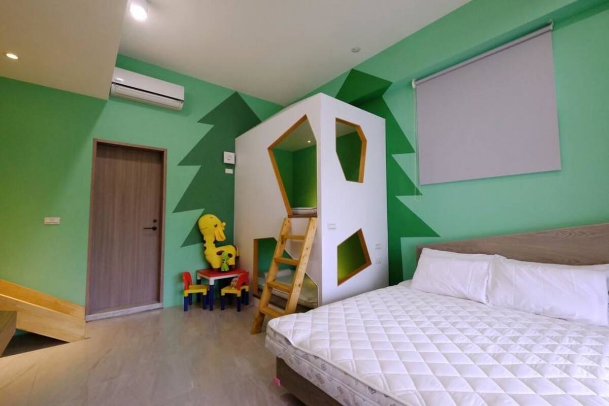 A bedroom with a bed, a wooden ladder, a small table with chairs, and a door.