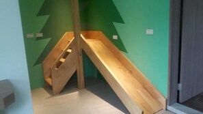 A room with a wooden staircase and a green wall with a lightning bolt design.