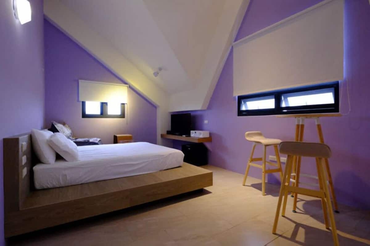 A bedroom with a bed, a TV, and a desk with a chair.