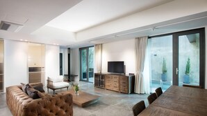 A modern living room with a leather sofa, a wooden coffee table, a TV on a wooden cabinet, and a dining table with chairs. - Jeonju Hotel Barahan (Jeonju)