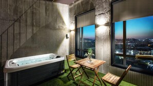 A modern room with a large window, a hot tub, and a wooden table with chairs. - Jeonju Hotel Barahan (Jeonju)