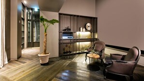 A modern living room with a wooden floor, a potted plant, a sofa, a chair, and a small table. - Jeonju Hotel Barahan (Jeonju)
