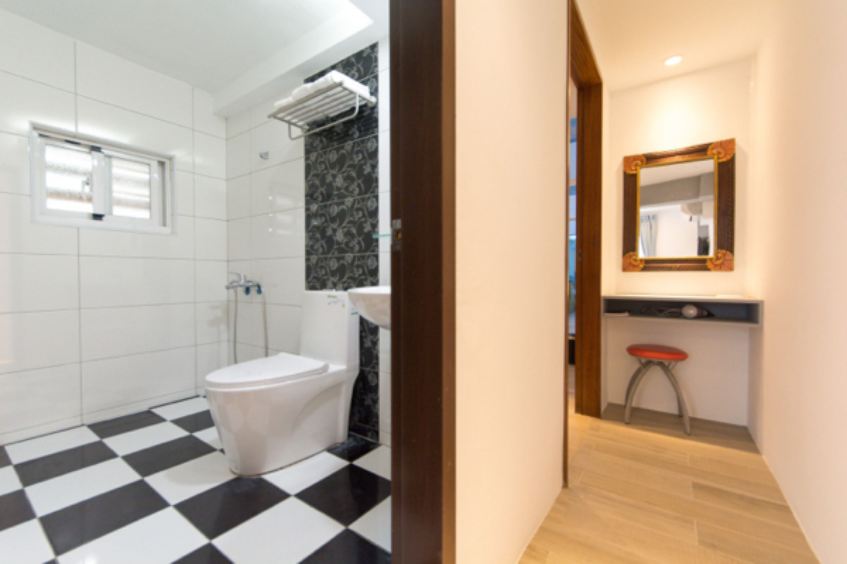 A bathroom with a checkered floor, a toilet, a sink, and a mirror.