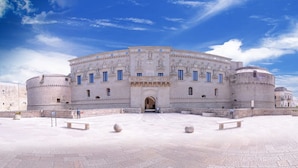 A historic building with a central entrance, two round towers, and a courtyard with benches. - ZO.NE. Baroque B&B (Lecce)