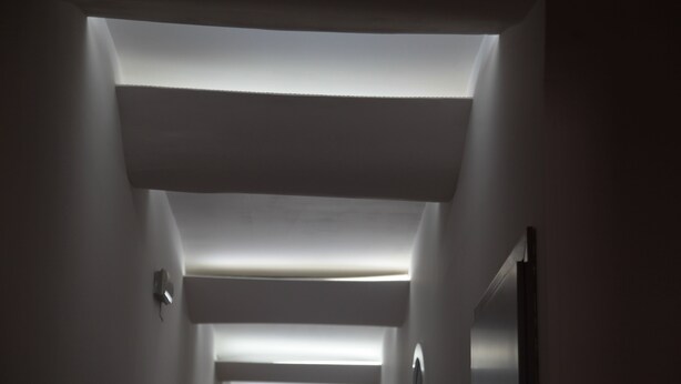 A narrow, dimly lit hallway with a sloped ceiling and recessed lighting. - ZO.NE. Baroque B&B (Lecce)