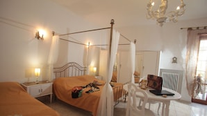A four-poster bed with a canopy, bedside tables with lamps, a small table with a chair, and a radiator. - ZO.NE. Baroque B&B (Lecce)