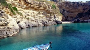 A small boat tied to a rocky shore in a clear blue body of water. - ZO.NE. Baroque B&B (Lecce)