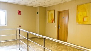 A hallway with a metal railing, beige walls, and two doors. - Hotel María Luisa (Algeciras)