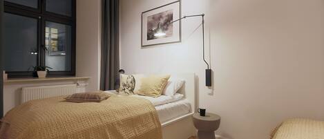 A bedroom with a bed, bedside table, lamp, window, and a framed picture on the wall.