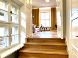 A staircase leading to a living area with a sofa, a table, and a window with curtains.