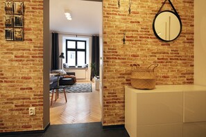 A room with a brick wall, a large mirror, and a woven basket on a white console. - Luxury Mint Apartments Main Square (Kraków)